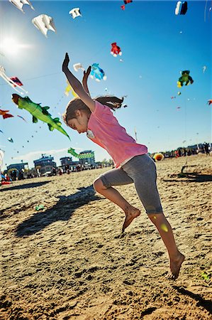 Young girl doing cartwheel on beach, kites flying in sky behind her, Rimini, italy Stock Photo - Premium Royalty-Free, Code: 649-08924700