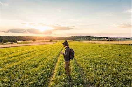 simsearch:614-05557077,k - Mid adult man, standing in field, holding SLR camera, looking at view, Neulingen, Baden-Württemberg, Germany Stock Photo - Premium Royalty-Free, Code: 649-08922738