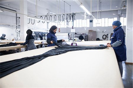 Factory workers unrolling textiles on work table in clothing factory Foto de stock - Sin royalties Premium, Código: 649-08922787