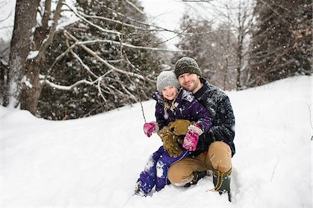 Portrait of mid adult man crouching in snow hugging daughter Stock Photo - Premium Royalty-Free, Code: 649-08923101
