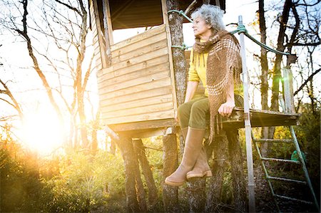 simsearch:649-08924209,k - Mature woman looking out from woodland treehouse at sunset Stock Photo - Premium Royalty-Free, Code: 649-08923219
