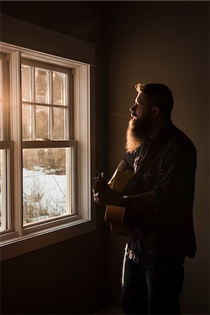 simsearch:6113-06909277,k - Man playing guitar beside window Stock Photo - Premium Royalty-Free, Code: 649-08923472