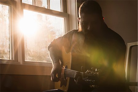 Man playing guitar beside window Stock Photo - Premium Royalty-Free, Code: 649-08923473