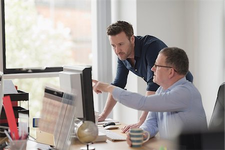 Male colleagues in discussion at office desk Stock Photo - Premium Royalty-Free, Code: 649-08923638