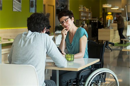Woman in wheelchair, sitting at restaurant table with friend Stock Photo - Premium Royalty-Free, Code: 649-08923725