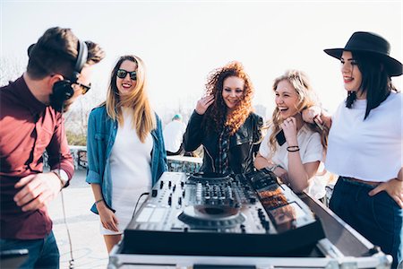 dj woman - Young man using mixing desk at roof party, group of young women standing around him Stock Photo - Premium Royalty-Free, Code: 649-08949658