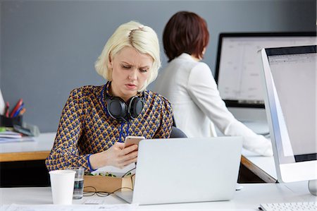 simsearch:649-06845199,k - Female designer looking at smartphone during working lunch at office desk Stock Photo - Premium Royalty-Free, Code: 649-08950782