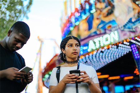 Two friends at funfair, holding smartphones Stock Photo - Premium Royalty-Free, Code: 649-08950960
