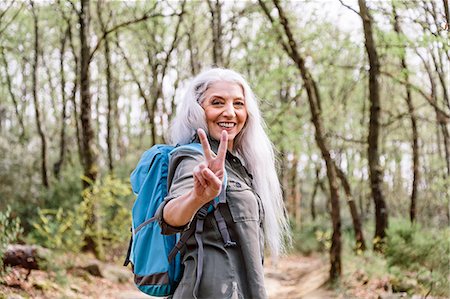 simsearch:649-08086253,k - Portrait of mature female backpacker giving peace sign in forest, Scandicci, Tuscany, Italy Stock Photo - Premium Royalty-Free, Code: 649-08951145
