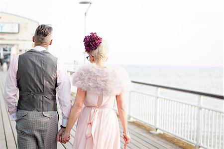 Rear view of 1950's vintage style couple strolling hand in hand on pier Stock Photo - Premium Royalty-Free, Code: 649-08951184