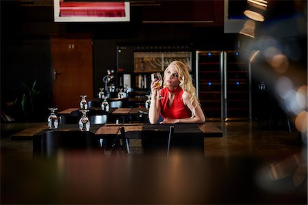 simsearch:614-06896619,k - Glamorous young woman with long blond hair sitting alone at restaurant table Foto de stock - Sin royalties Premium, Código: 649-08969416