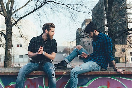 simsearch:649-08702620,k - Two young male hipsters sitting on wall looking at smartphone Stock Photo - Premium Royalty-Free, Code: 649-08969962