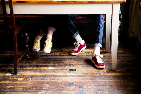 Jeans and trainers worn by couple sitting at table Stock Photo - Premium Royalty-Free, Code: 649-08987968