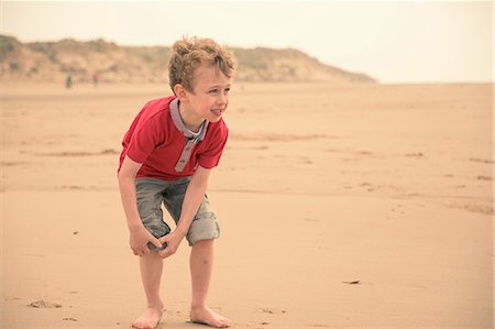 Boy rolling up his jeans on beach Foto de stock - Sin royalties Premium, Código: 649-08987993