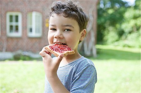 Boy eating bread with jam outdoors Stock Photo - Premium Royalty-Free, Code: 649-09002849