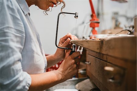 sawing - Cropped view of female jeweller using coping saw at workbench Stock Photo - Premium Royalty-Free, Code: 649-09016556