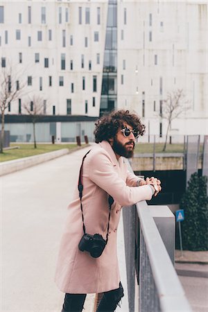 simsearch:614-08392638,k - Young man standing on bridge, looking at view, camera over shoulder Stock Photo - Premium Royalty-Free, Code: 649-09025590