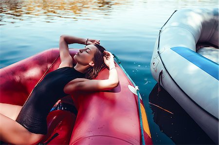 simsearch:649-09078617,k - Woman wearing swimsuit lying in boat looking away Stock Photo - Premium Royalty-Free, Code: 649-09025996