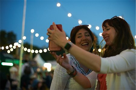 Two mature female friends taking smartphone selfie at night market festival in park, London, UK Stock Photo - Premium Royalty-Free, Code: 649-09026264