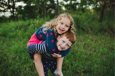 simsearch:614-07806393,k - Portrait of boy giving sister a piggyback in field Stock Photo - Premium Royalty-Free, Code: 649-09035528