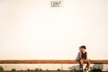 simsearch:649-06533379,k - Boy sitting on wall outside white church Photographie de stock - Premium Libres de Droits, Code: 649-09036344