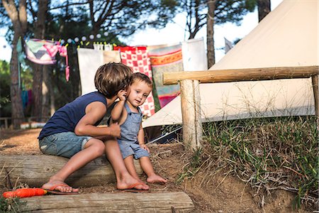 Male toddler being kissed on cheek by his big brother on campsite Stock Photo - Premium Royalty-Free, Code: 649-09061255
