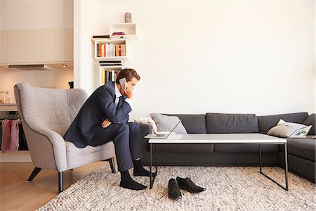 full body cell - Businessman sitting on armchair using laptop and making smartphone call Stock Photo - Premium Royalty-Free, Code: 649-09061446