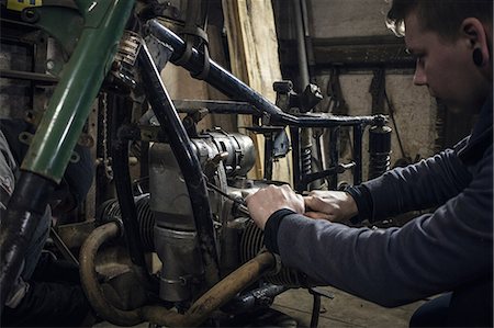 Mechanic repairing vintage motorcycle engine in workshop Stock Photo - Premium Royalty-Free, Code: 649-09077970