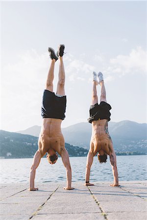 Two young men doing handstands on waterfront, Lake Como, Lombardy, Italy Stock Photo - Premium Royalty-Free, Code: 649-09078275