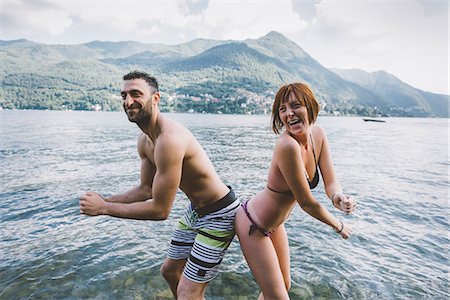 Portrait of couple in swimwear buttock to buttock in Lake Como, Lombardy, Italy Stock Photo - Premium Royalty-Free, Code: 649-09078289