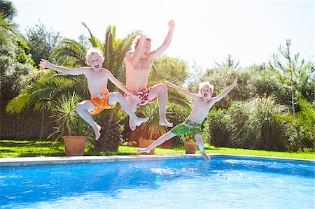 simsearch:649-06812049,k - Father and sons in mid air jumping into outdoor swimming pool Stock Photo - Premium Royalty-Free, Code: 649-09078549