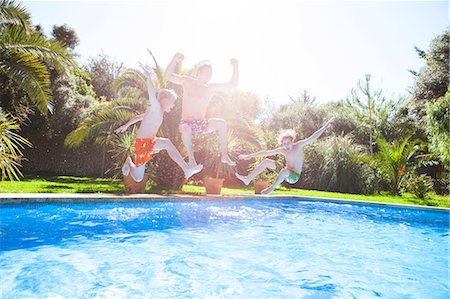 simsearch:649-06812049,k - Father and sons in mid air jumping into outdoor swimming pool Stock Photo - Premium Royalty-Free, Code: 649-09078550