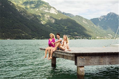 Friends sitting together on edge of pier, Innsbruck, Tirol, Austria, Europe Stock Photo - Premium Royalty-Free, Code: 649-09111239