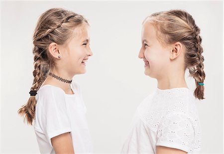 Studio portrait of two girls with hair plaits face to face, head and shoulders Stock Photo - Premium Royalty-Free, Code: 649-09111669