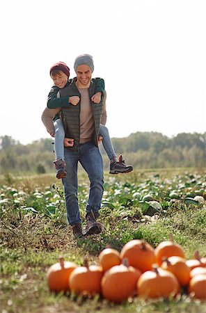 fall pumpkin - Man giving son piggyback ride in field at pumpkin patch Stock Photo - Premium Royalty-Free, Code: 649-09123597