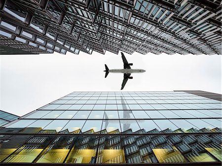 Low angle view of airplane flying  between modern buildings, London City Airport, London, UK Stock Photo - Premium Royalty-Free, Code: 649-09123611