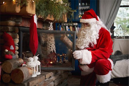 Santa Claus, indoors, putting log on fire Stock Photo - Premium Royalty-Free, Code: 649-09123667