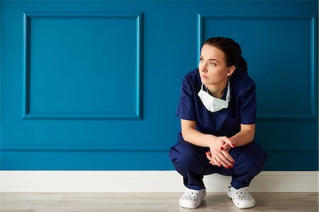 sad and missing someone - Portrait of female surgeon, crouching, looking away, pensive expression Stock Photo - Premium Royalty-Free, Code: 649-09123930