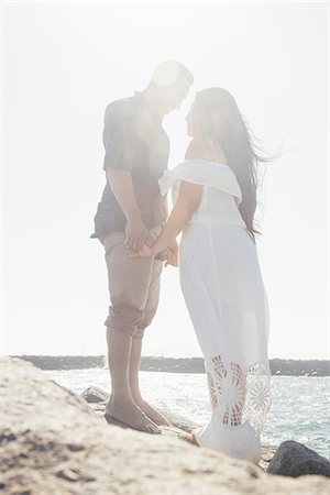 simsearch:649-08239088,k - Couple standing on coastal rocks, holding hands, face to face, Seal Beach, California, USA Stock Photo - Premium Royalty-Free, Code: 649-09139191