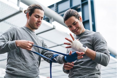 Identical male adult twin boxers training outdoors, bandaging hands with hand wraps Stock Photo - Premium Royalty-Free, Code: 649-09148665