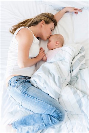 Mother kissing sleeping baby in bed Stock Photo - Premium Royalty-Free, Code: 649-09148795