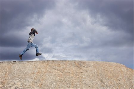 simsearch:700-00519358,k - Boy running on top of rock against stormy cloud sky Stock Photo - Premium Royalty-Free, Code: 649-09166462