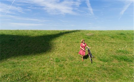 Girl and bicycle beside shadow of modern wind turbine Stock Photo - Premium Royalty-Free, Code: 649-09166913