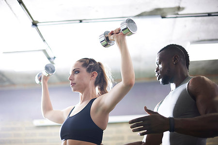 simsearch:693-08126938,k - Trainer watching female client lifting dumbbells in gym Stock Photo - Premium Royalty-Free, Code: 649-09176909