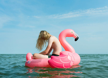 Boy on inflatable flamingo at sea Stock Photo - Premium Royalty-Free, Code: 649-09177187