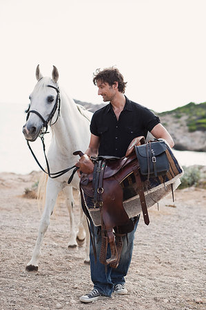 man carrying horses saddle Stock Photo - Premium Royalty-Free, Code: 649-09205631