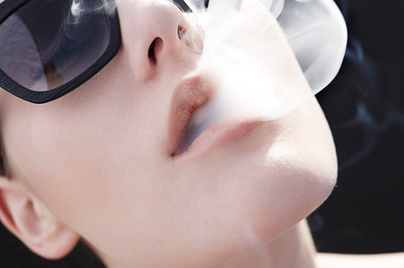 simsearch:649-07436630,k - Studio head shot of young woman exhaling cigarette smoke Stock Photo - Premium Royalty-Free, Code: 649-09207460