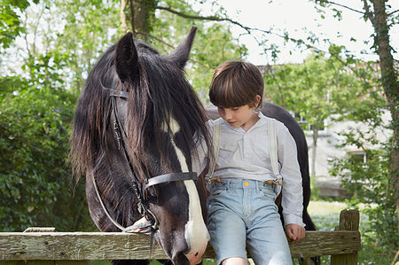 Portrait of boy sitting on farm gate with horse Stock Photo - Premium Royalty-Free, Code: 649-09208069