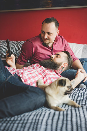 Gay couple with dog, using smartphone in bedroom Stock Photo - Premium Royalty-Free, Code: 649-09208856