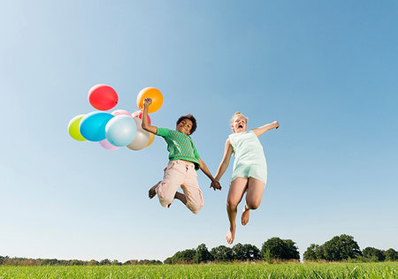 simsearch:649-07804176,k - Girl and boy holding bunch of balloons jumping mid air in field Stock Photo - Premium Royalty-Free, Code: 649-09208905